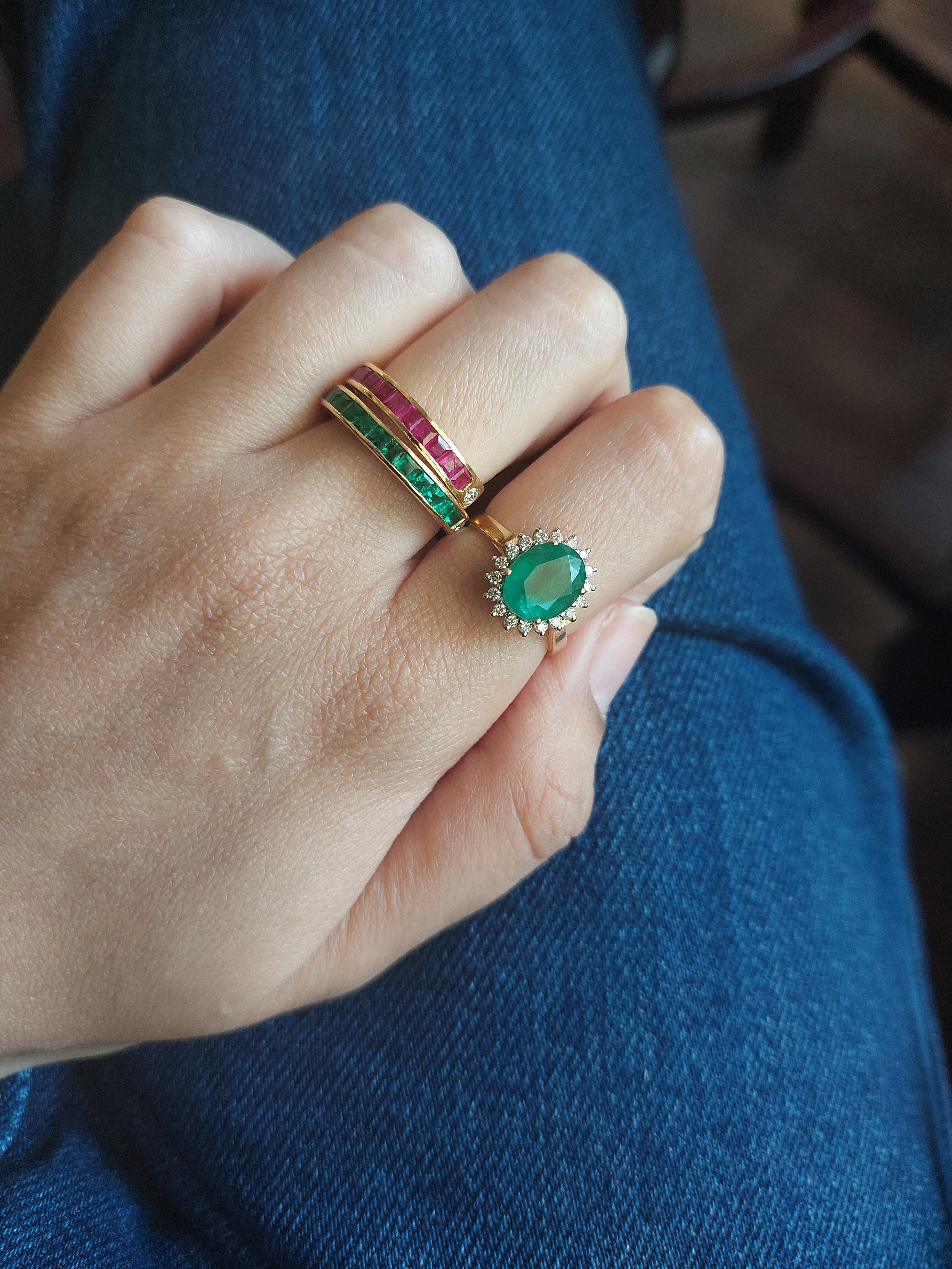 14K gold emerald diamond ring on hand next to gemstone bands