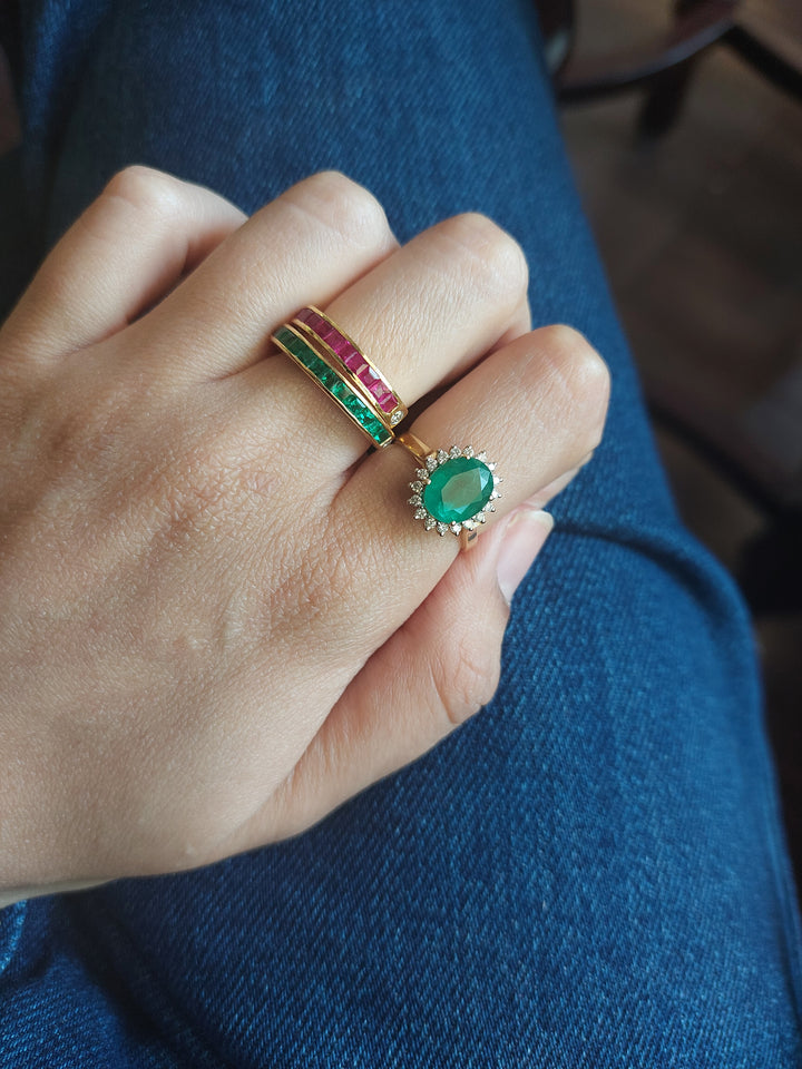 14K gold emerald diamond ring on hand next to gemstone bands