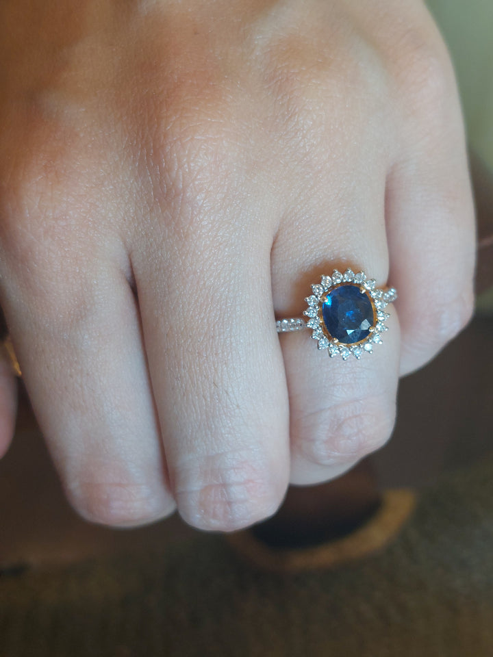 14K gold blue sapphire ring with diamond halo on finger