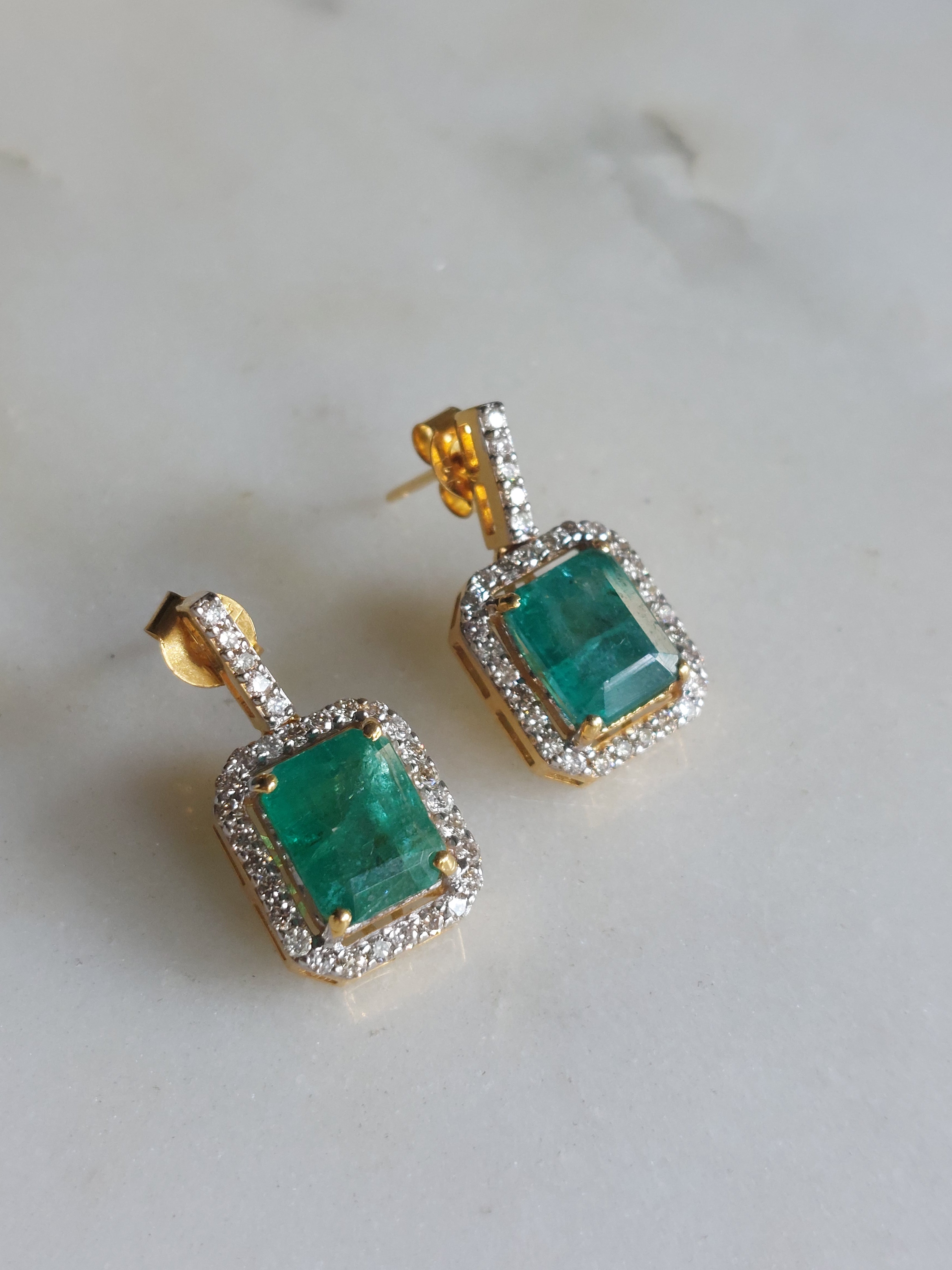 14K gold square emerald earrings on marble surface