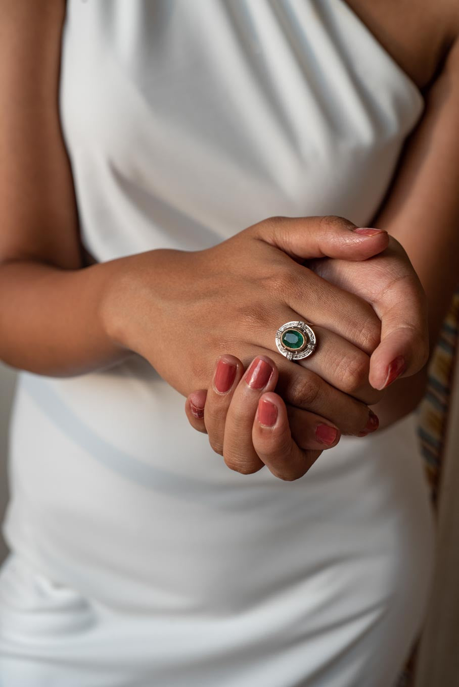 14K gold round emerald ring against white fabric