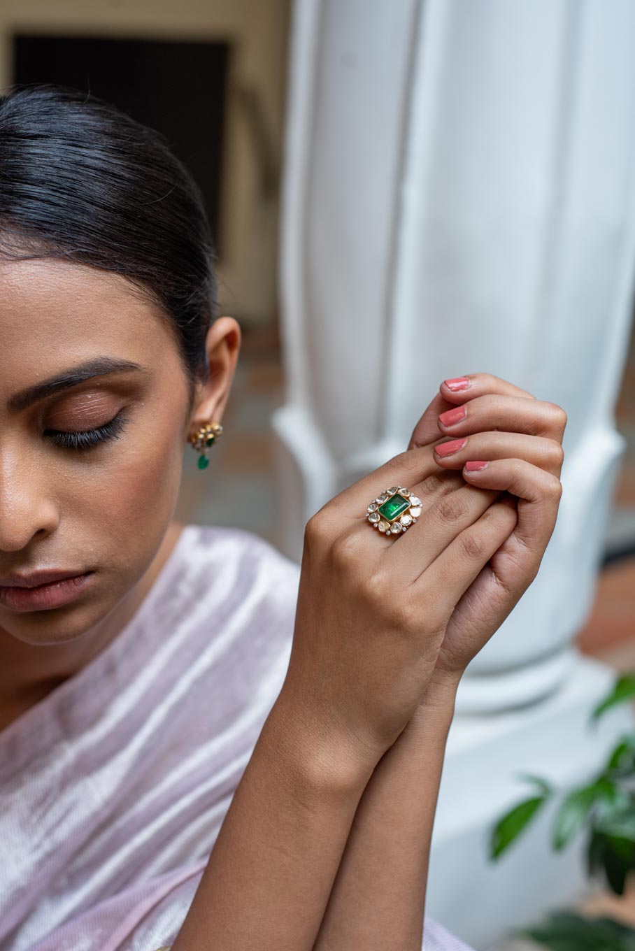14K gold emerald ring with diamond accents on finger