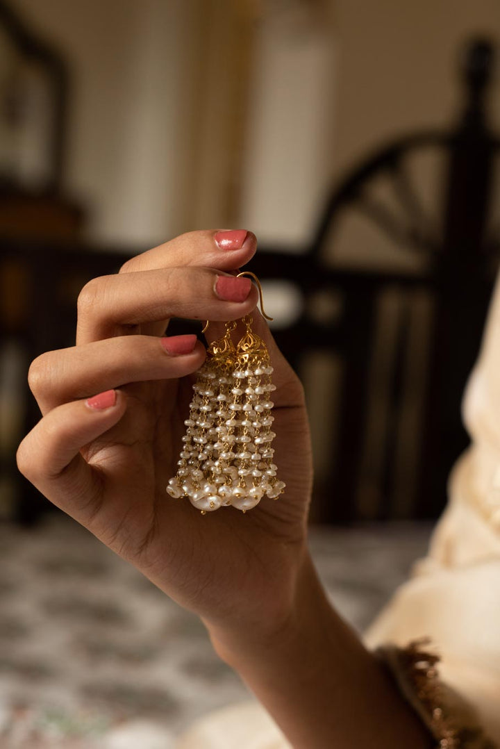 18K gold pearl jhumka earrings with gold accents held in hand