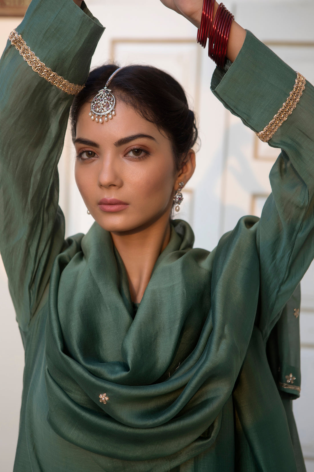Silver-toned diamond-studded maang tika with intricate filigree details worn on model's center-parted hair.