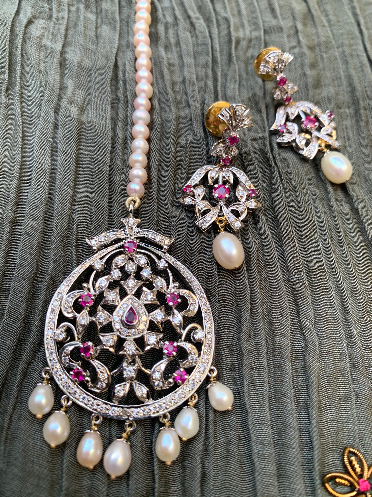 Silver Manik diamond tika with pink stones and hanging pearl drops, paired with matching earrings.