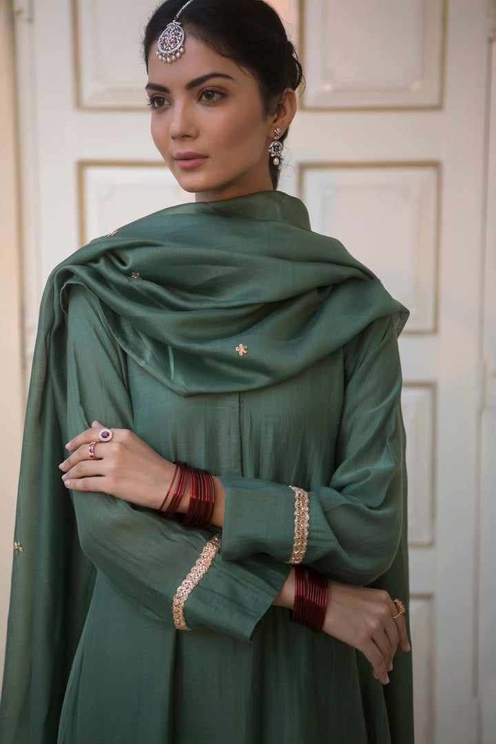 Silver diamond maangtika with intricate detailing worn with dark green traditional outfit and matching bangles.