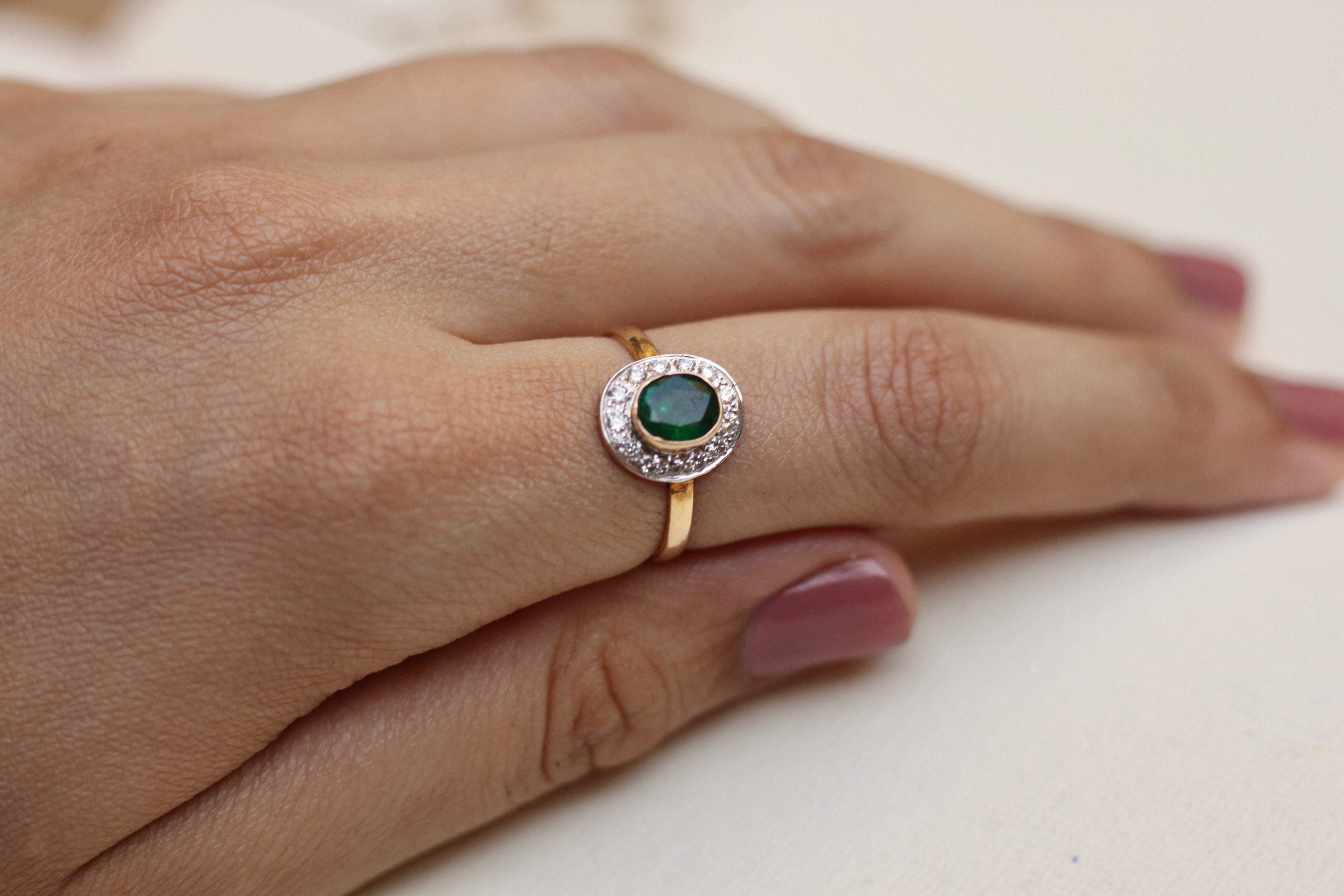 14K gold emerald ring with diamond halo on hand