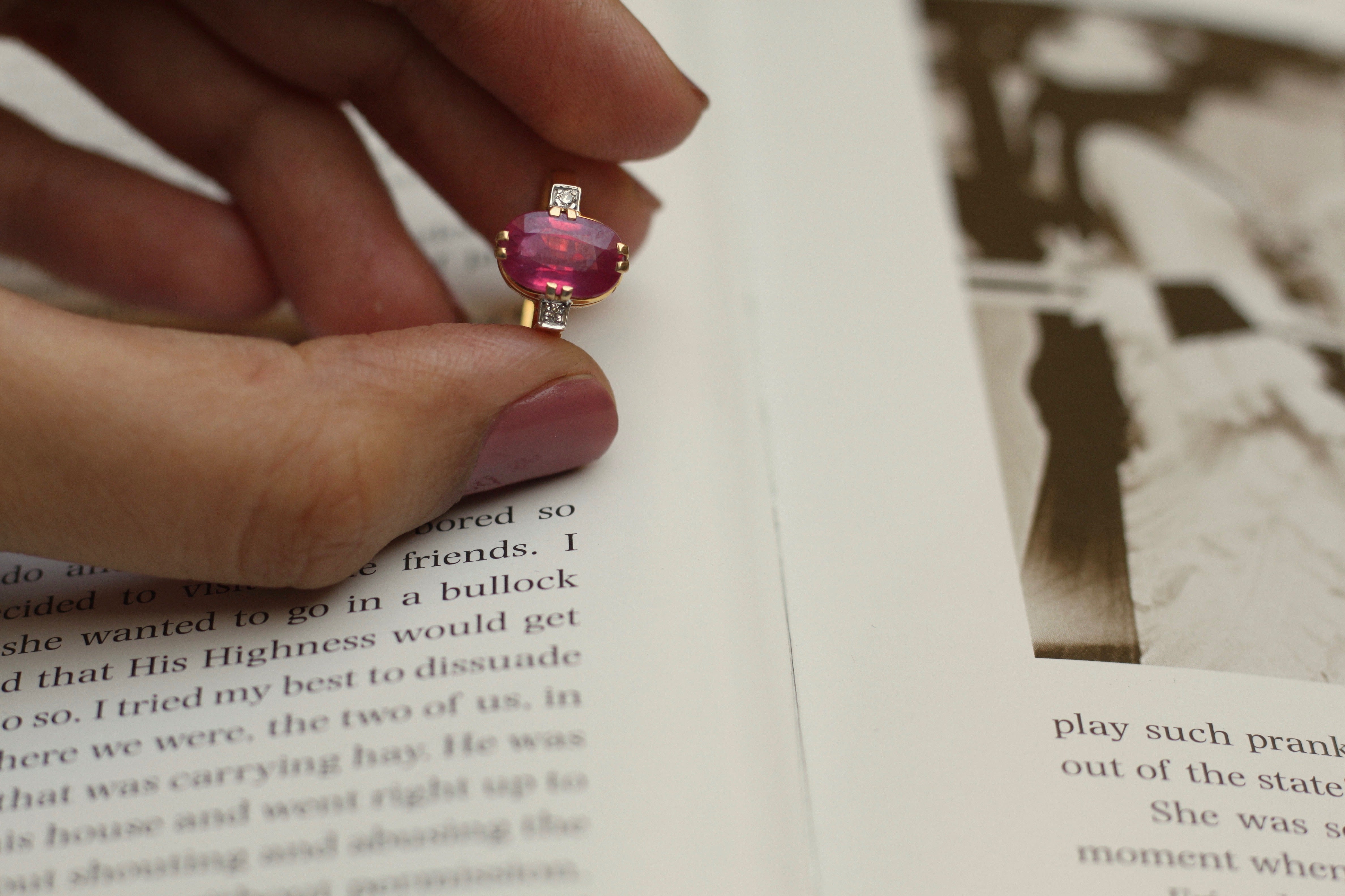 14K gold ruby ring pink gemstone held between fingers