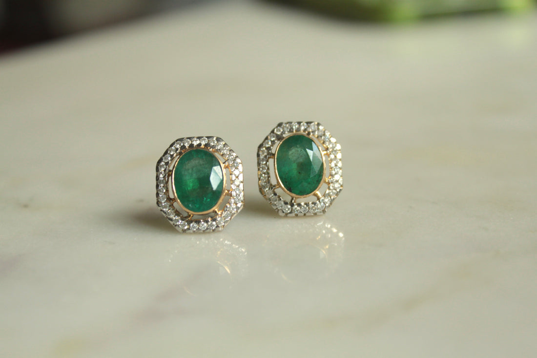 14K gold oval emerald earrings on marble surface