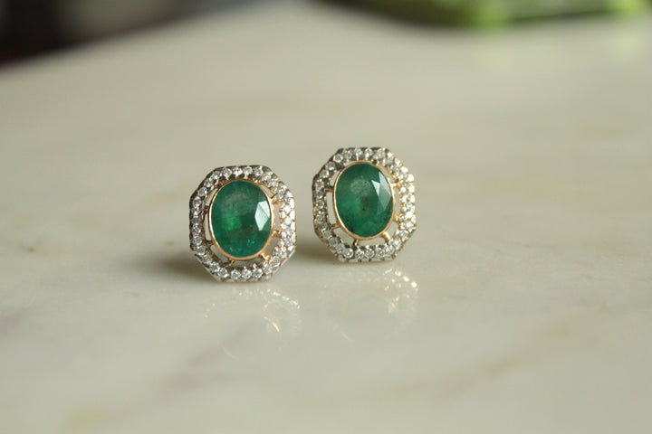 14K gold oval emerald earrings on marble surface