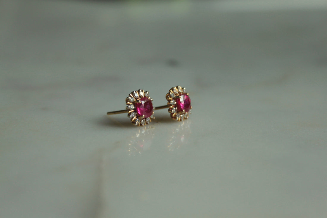 14K gold oval ruby stud earrings on marble surface
