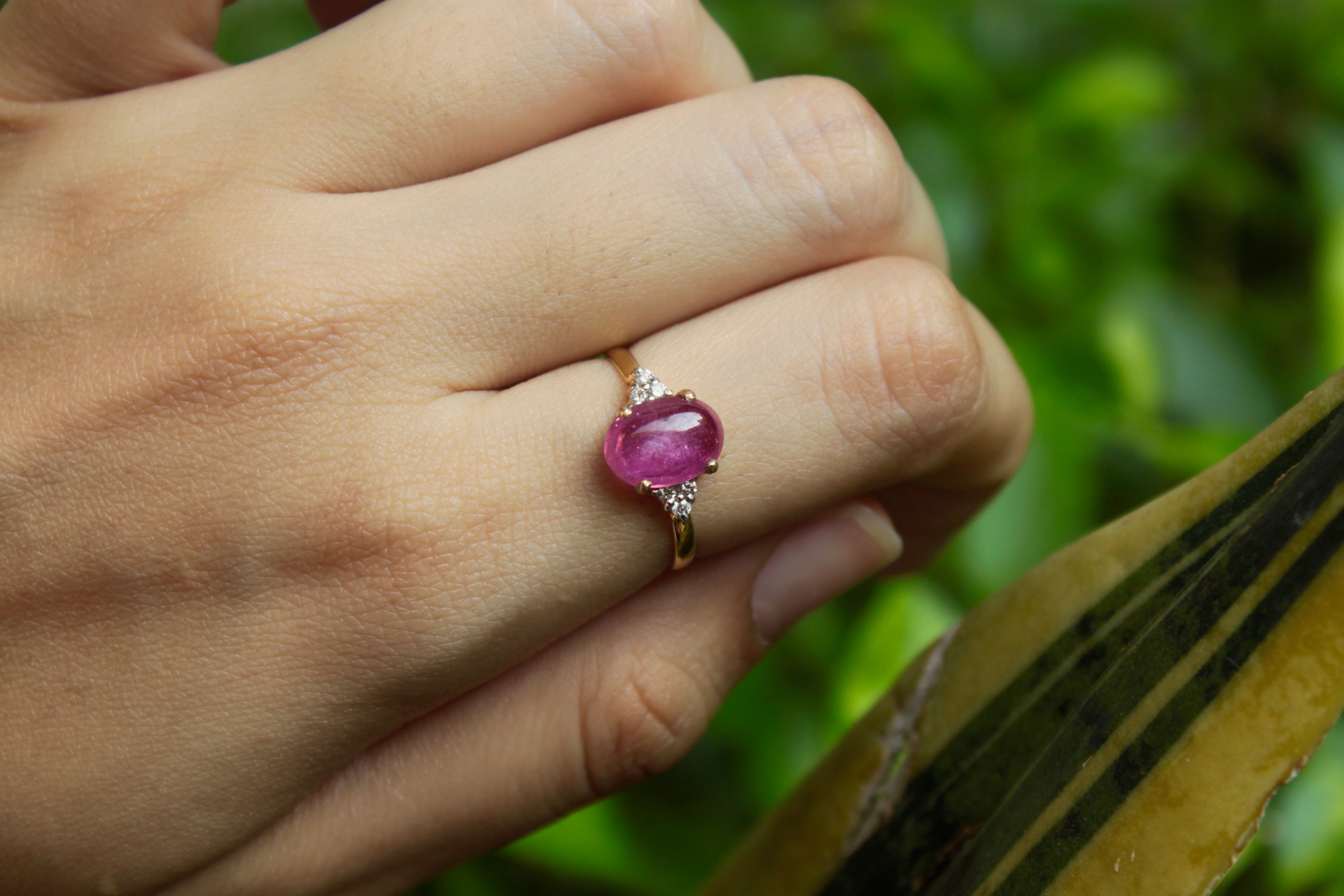 14K gold ruby ring worn on finger against green background