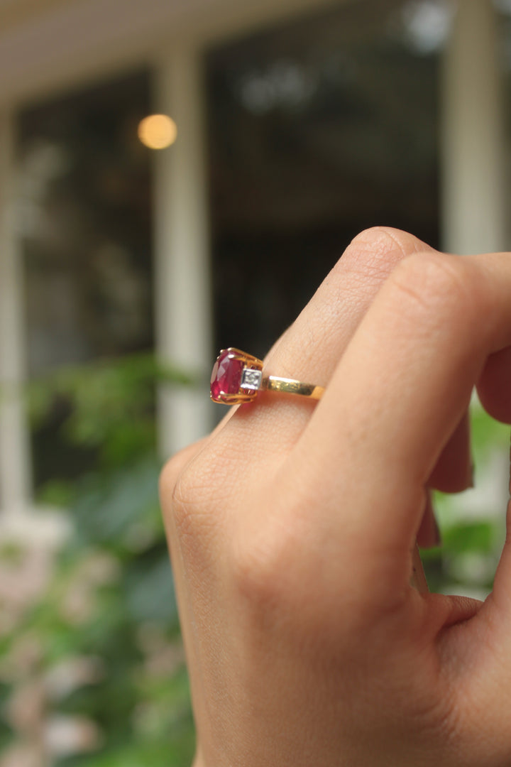 Gold ring featuring a rectangular pink gemstone with a slender band on a finger.